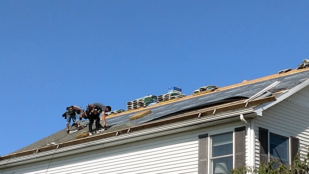 A group of men working on the roof of a house.