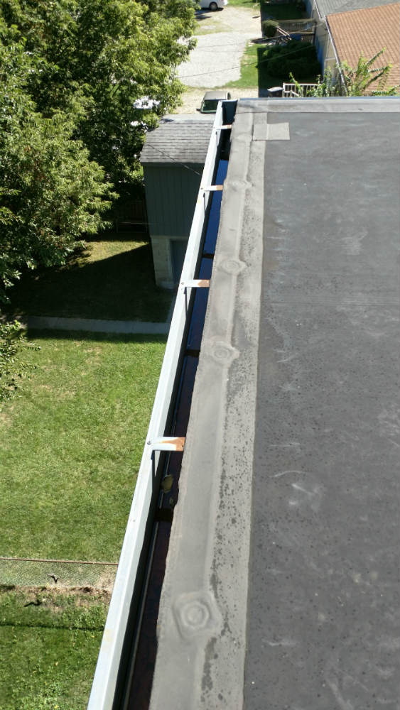 A gutter that is being installed on the side of a house.